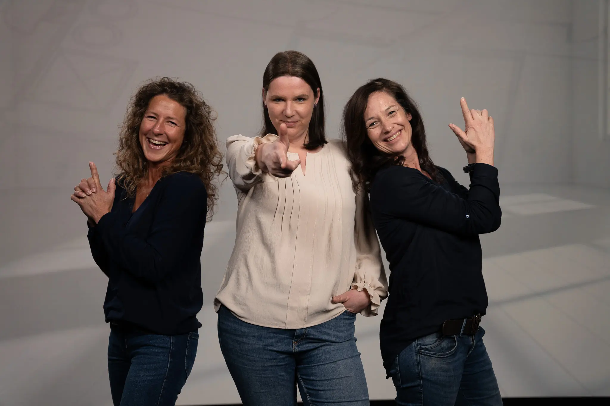 Annette Lambertz, Susanne Althoff und Sonja Hülsers stehen vor einem grauen Hintergrund und lächeln in die Kamera